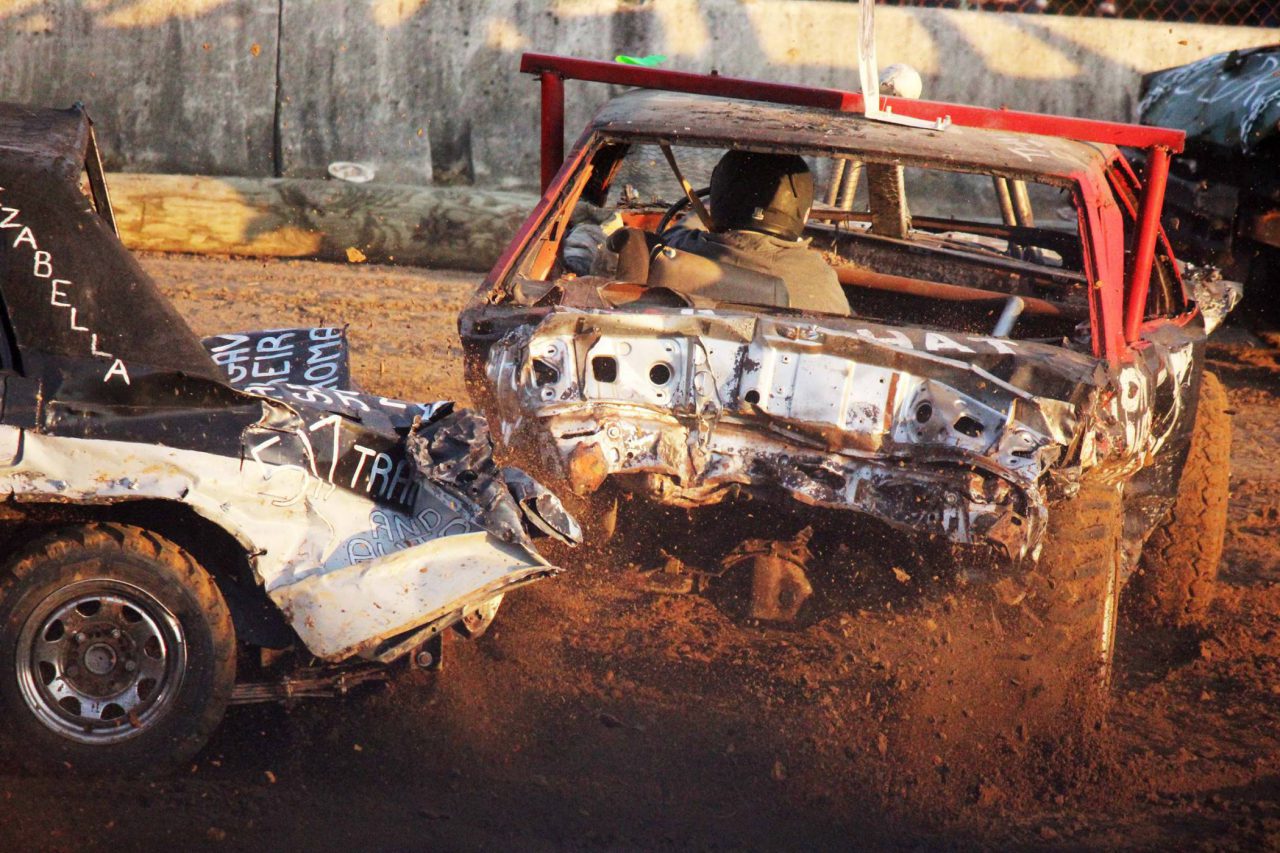 Impact derby competition driver in a red car with dirty flying.