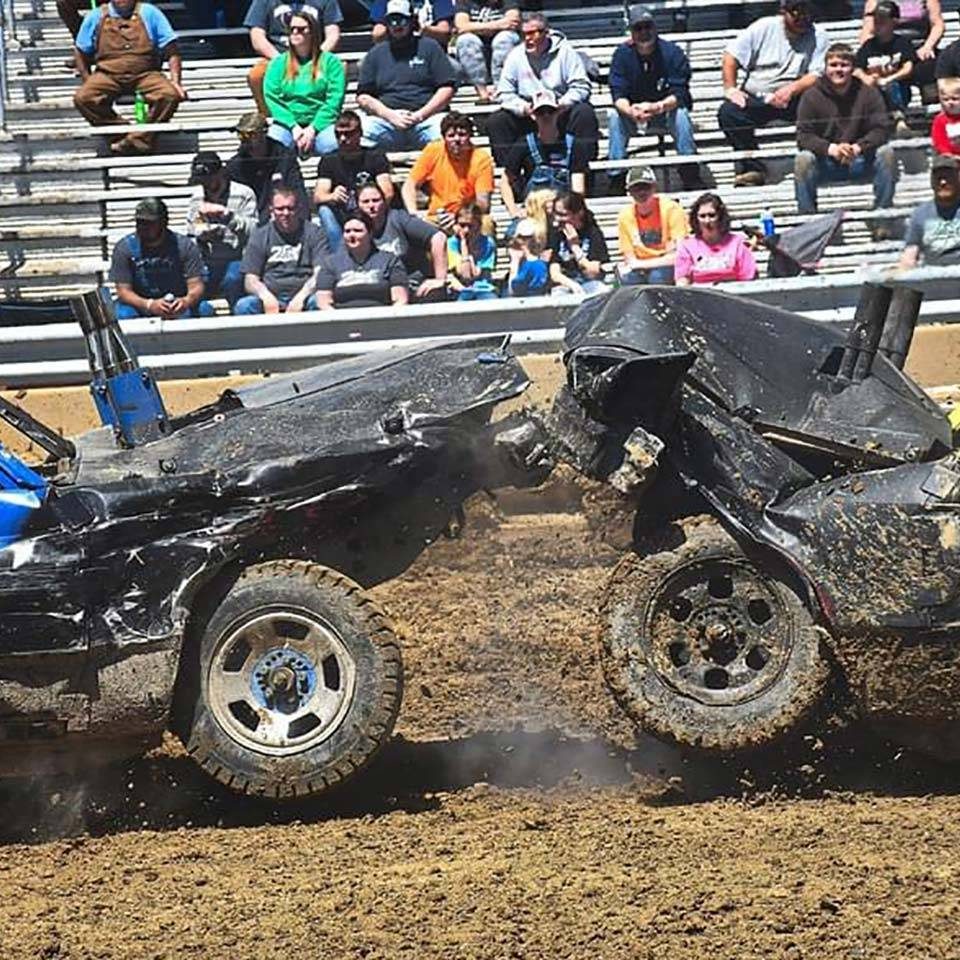 Two cars crashing into each other at a demolition derby competition.